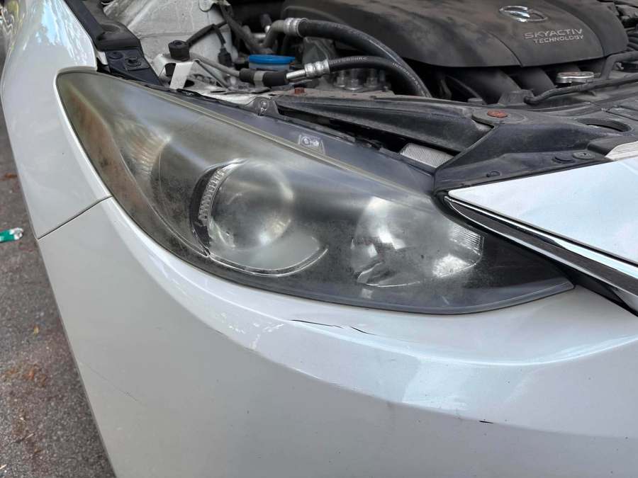 Foggy hazed headlight on a white Mazda before restoration