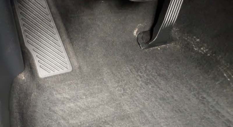 Dusty matted driver footwell carpet before cleaning